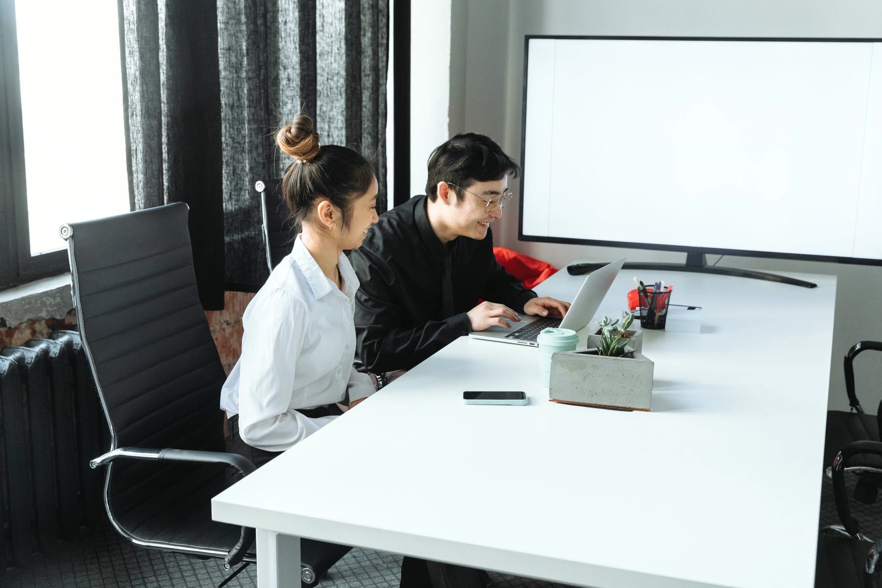 Two people discussing a project over a laptop